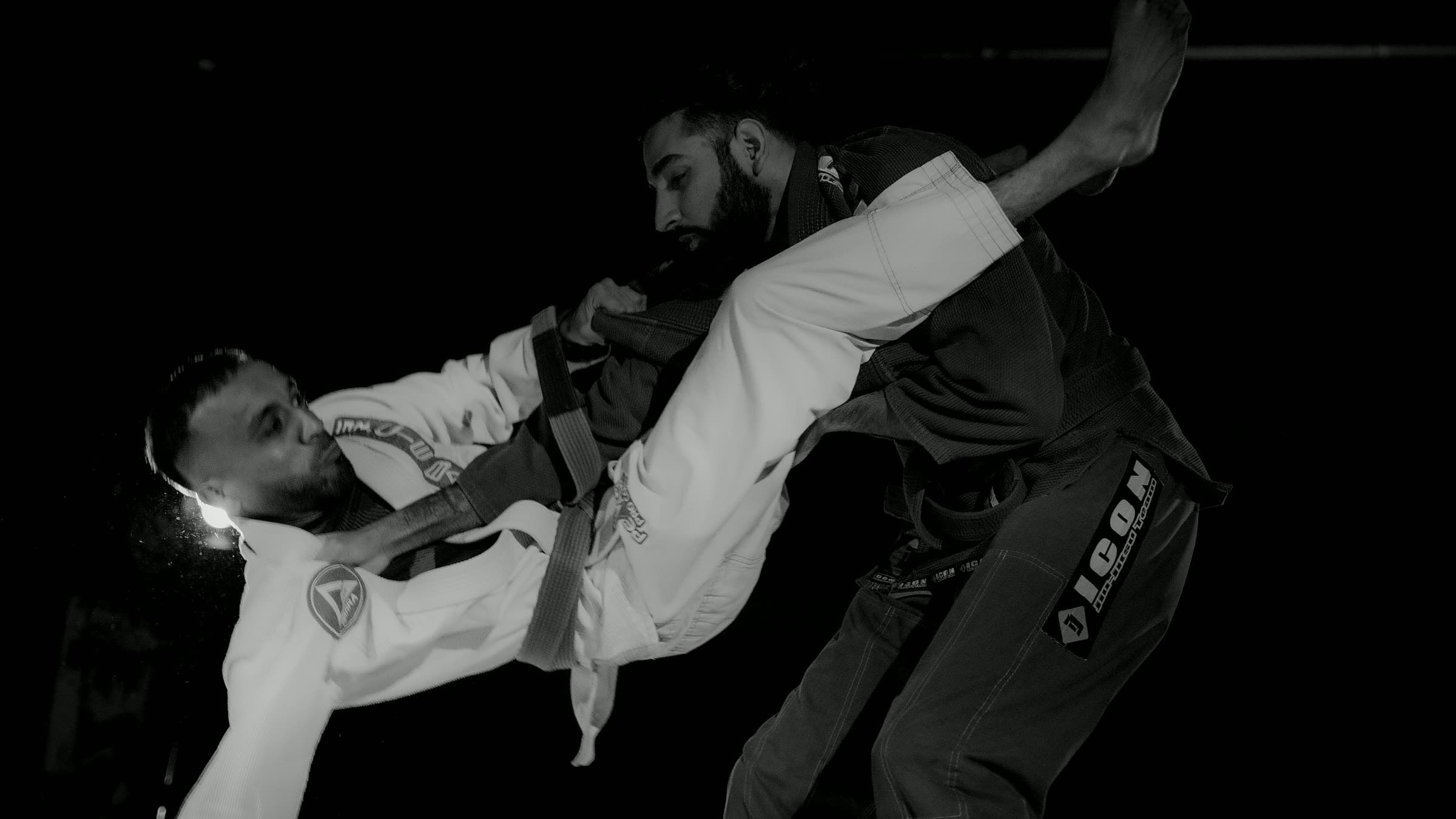 Brazilian jiu-jitsu — competition action shot, dark gi vs white gi