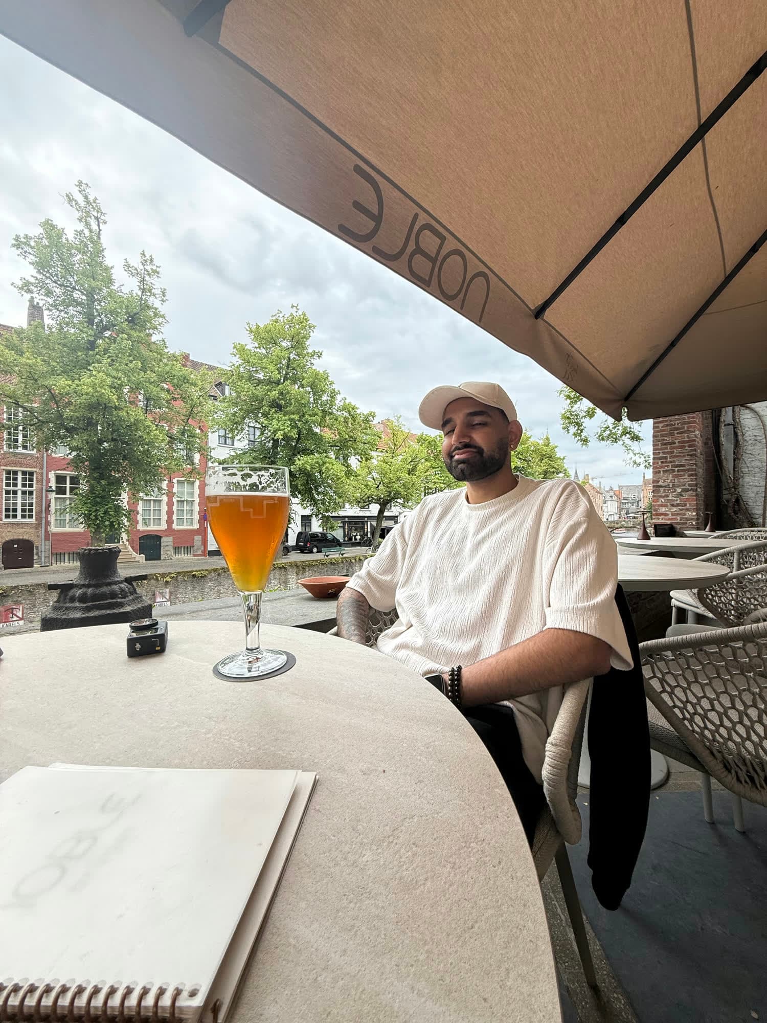 Me looking at the camera across a table with a tall glass of amber beer