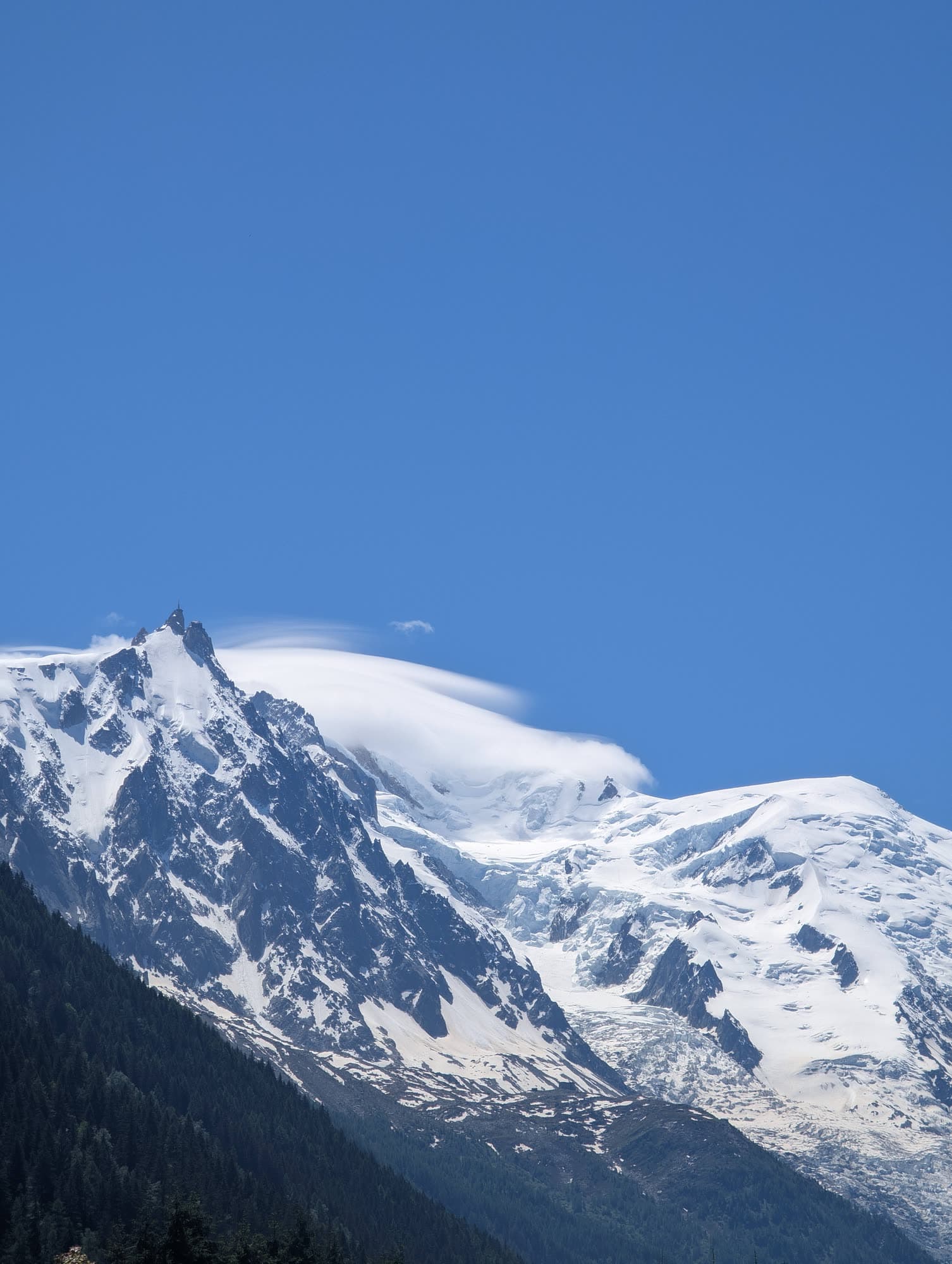 The Aiguille du Midi and the snowfields of Mont Blanc against a deep blue sky, a cap of cloud on the summit