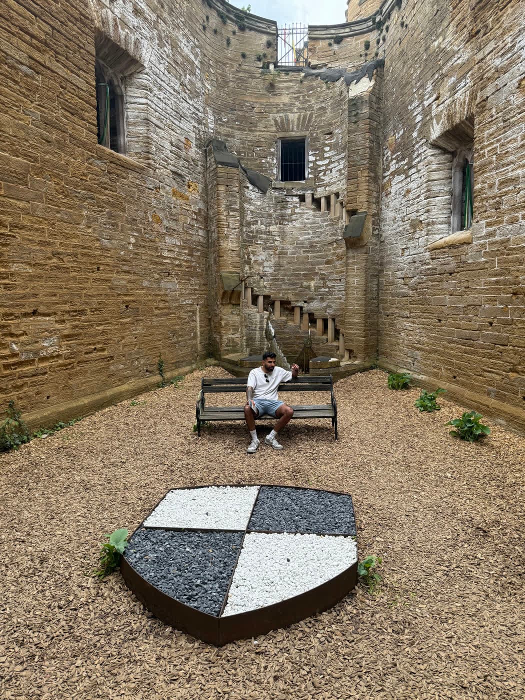 Me seated on a wooden bench behind the gravel shield, one arm raised