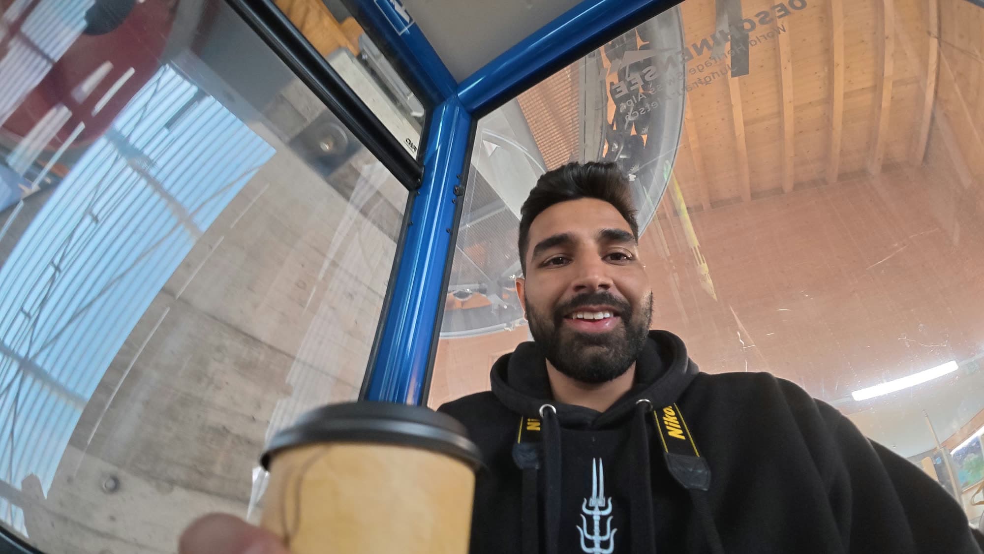Wide-angle selfie of me in a gondola cabin holding a coffee