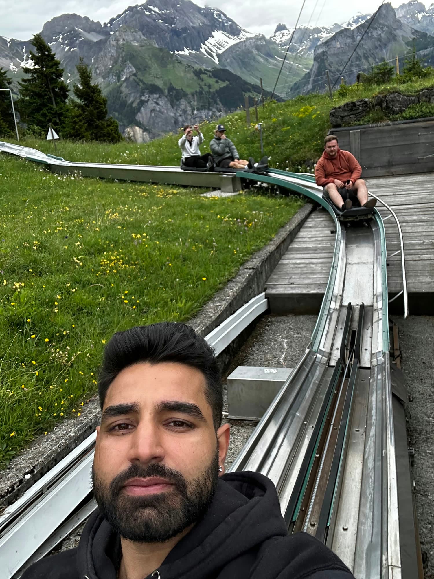 Selfie of me on the toboggan rail, the run winding down the meadow behind