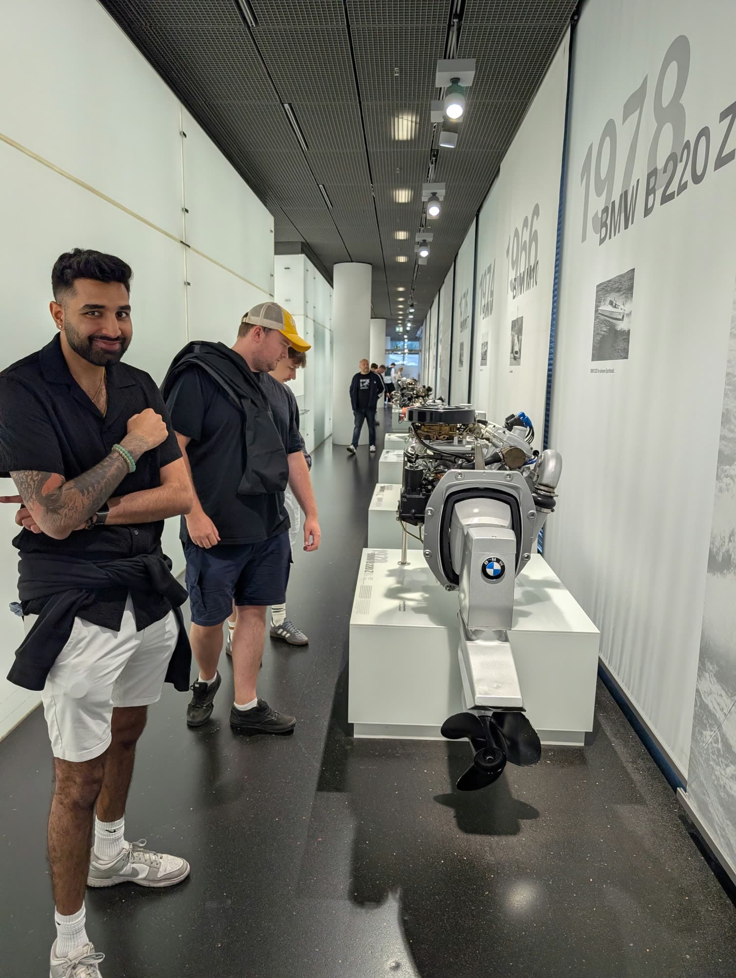 Me in a long white museum corridor lined with engines, arms crossed