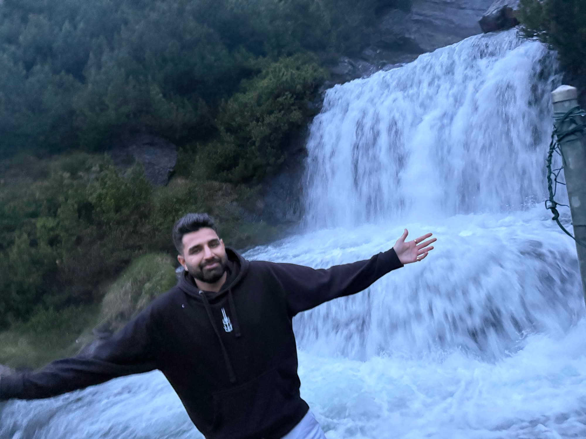Me with arms wide in front of the waterfall, white water filling the frame