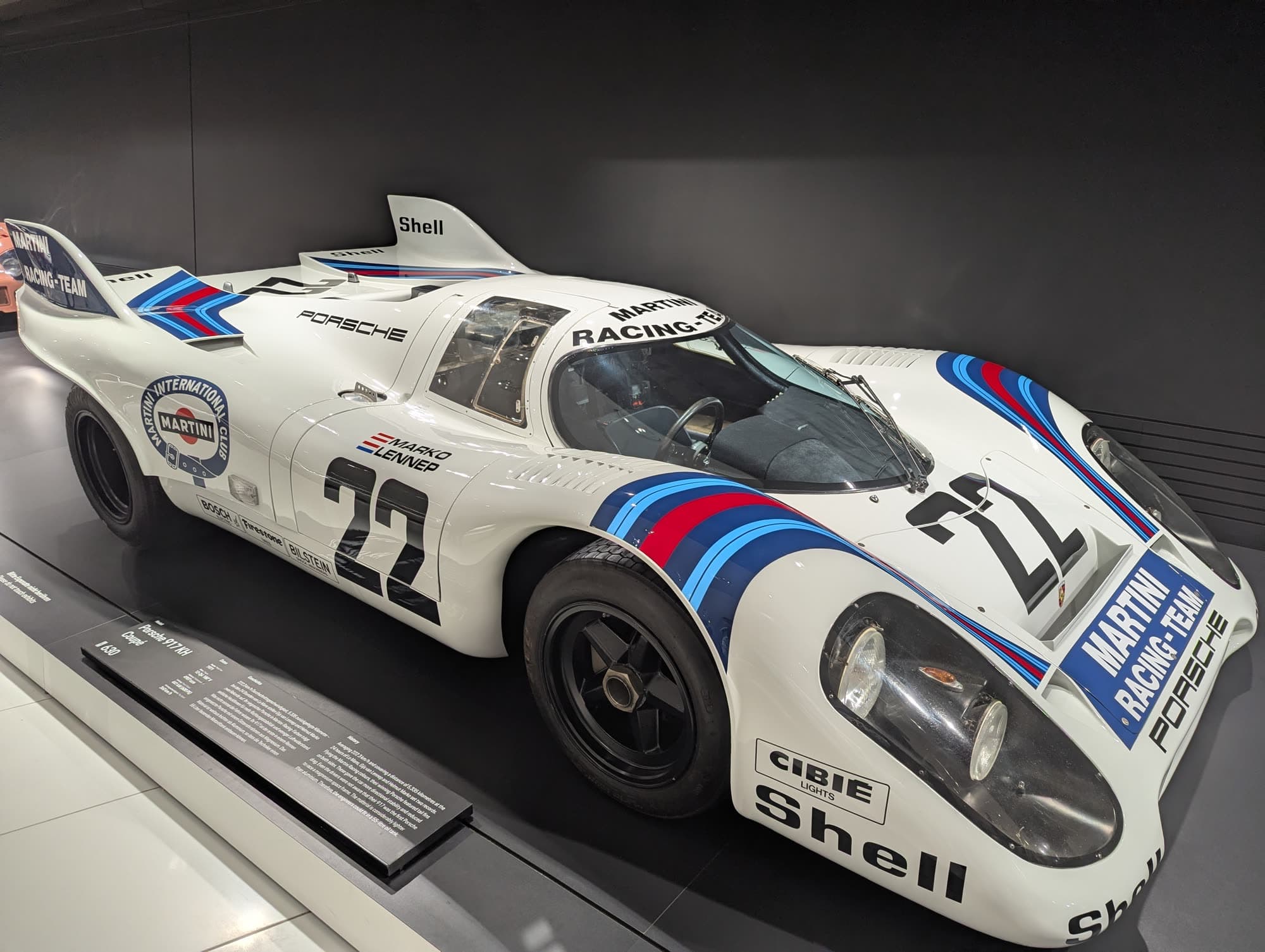 White Porsche 917 race car in Martini stripes, number 22, on the museum floor