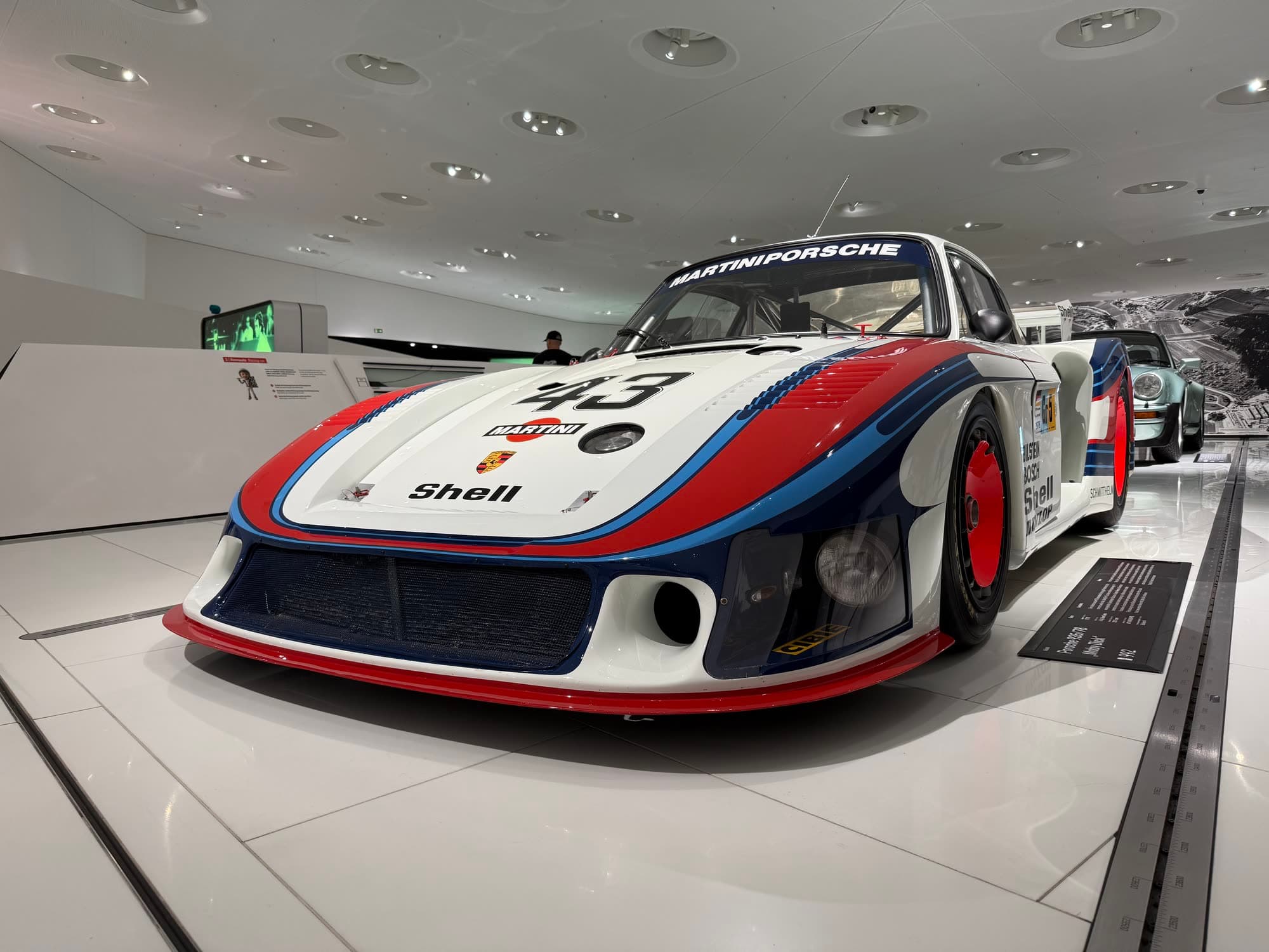 The white Porsche 935/78 in Martini stripes, number 43, under the museum lights