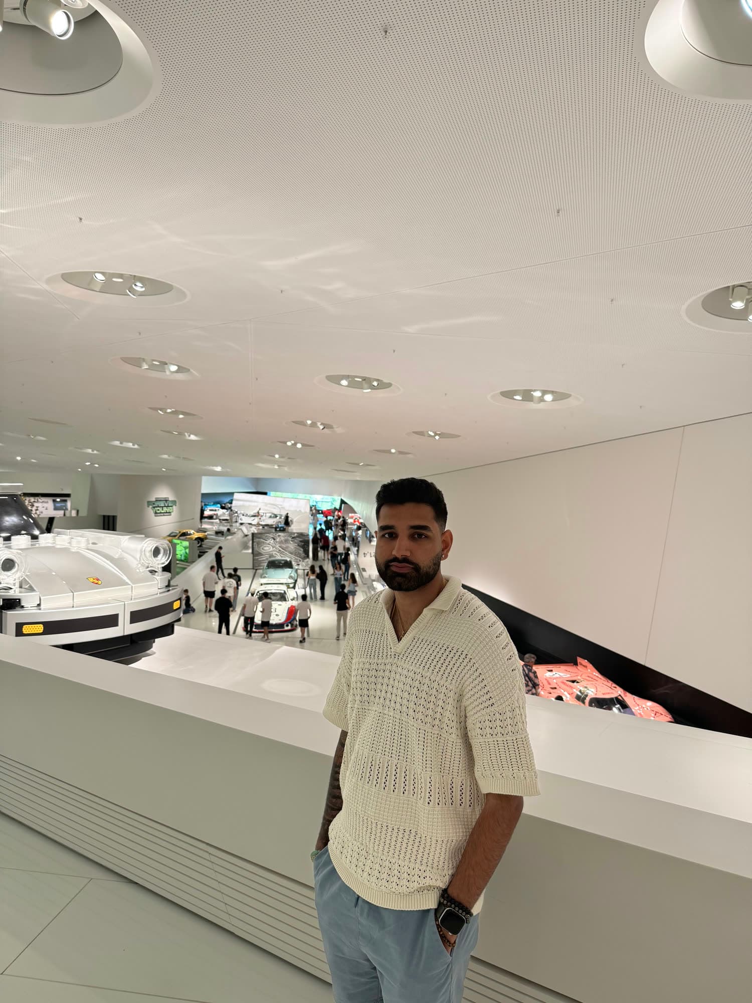 Me standing at a white balustrade above the museum hall, race cars below