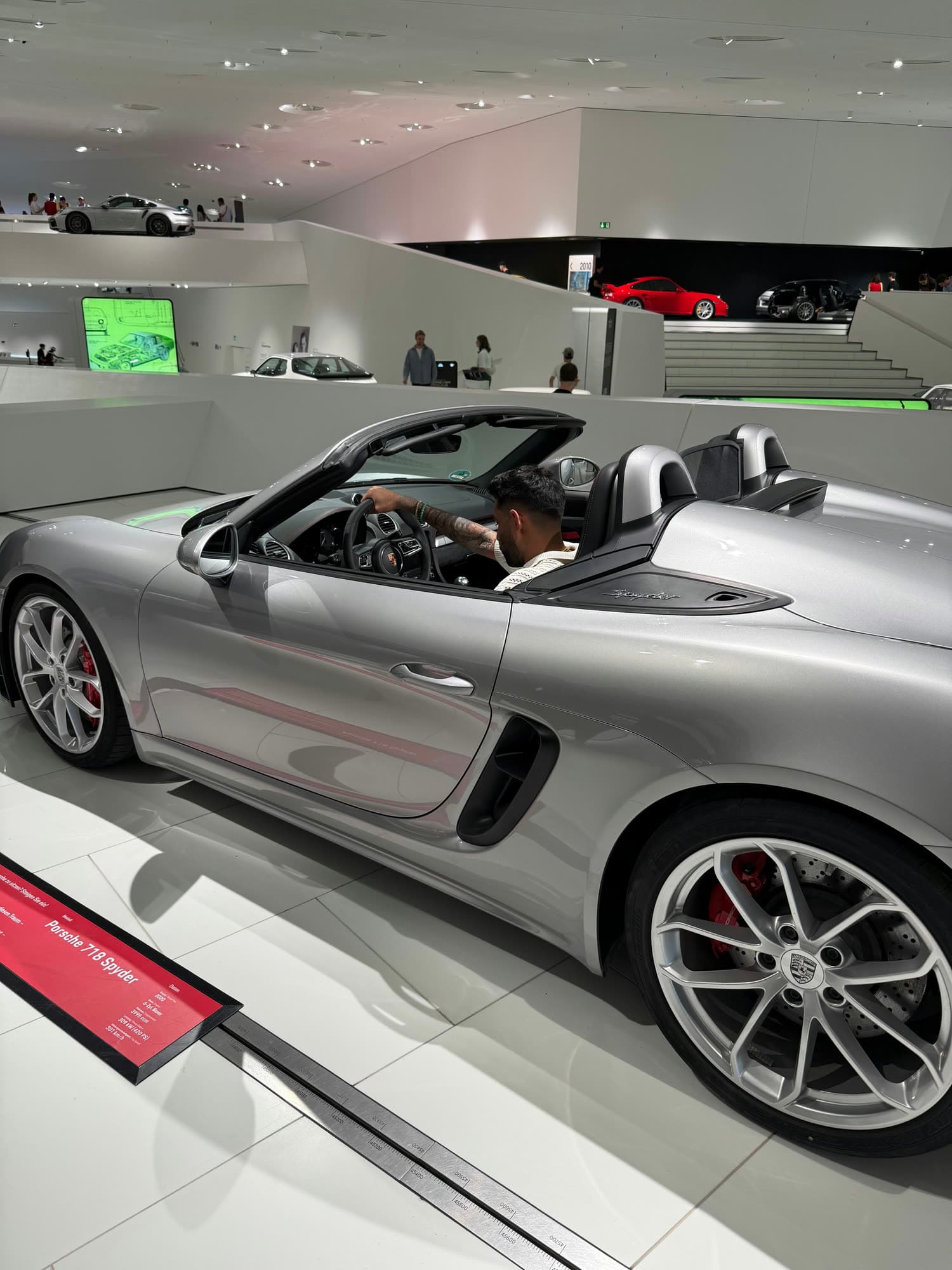 Me behind the wheel of a silver 718 Spyder on the museum floor