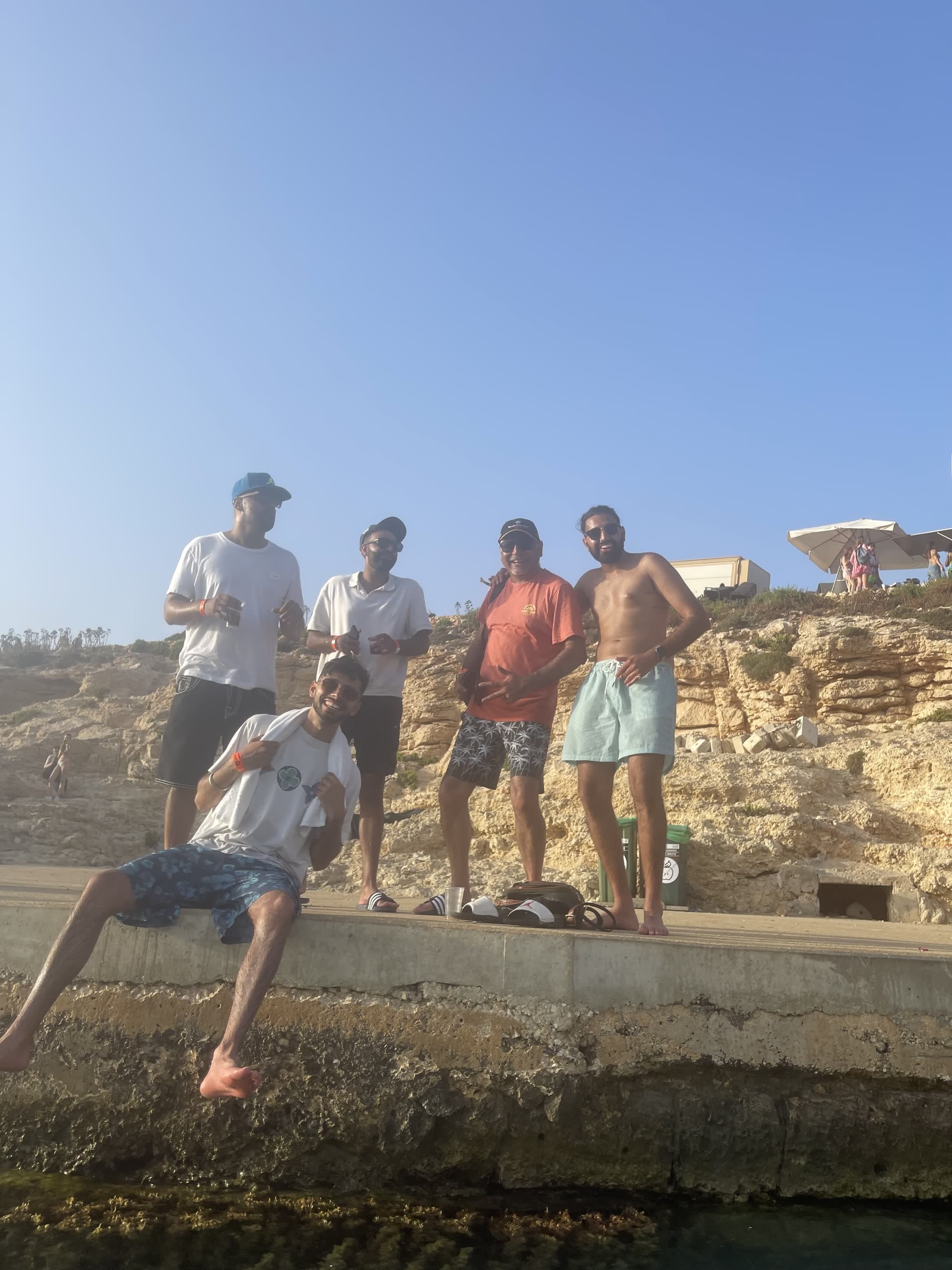 Five men on a concrete ledge above the water at the Blue Lagoon, me on the right in pale swim shorts with my hands on my hips