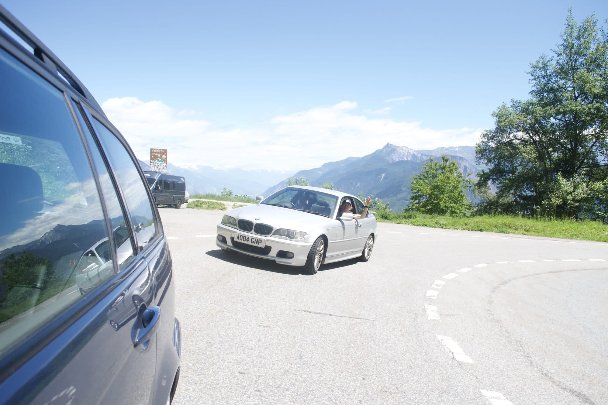 The silver BMW coupe coming round a hairpin behind the estate, a hand waving from the passenger window