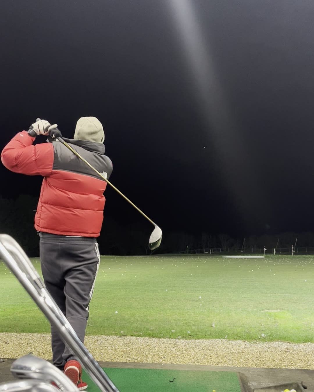 Param from behind in a full finish with the driver over his shoulder, the floodlit range stretching out into the dark