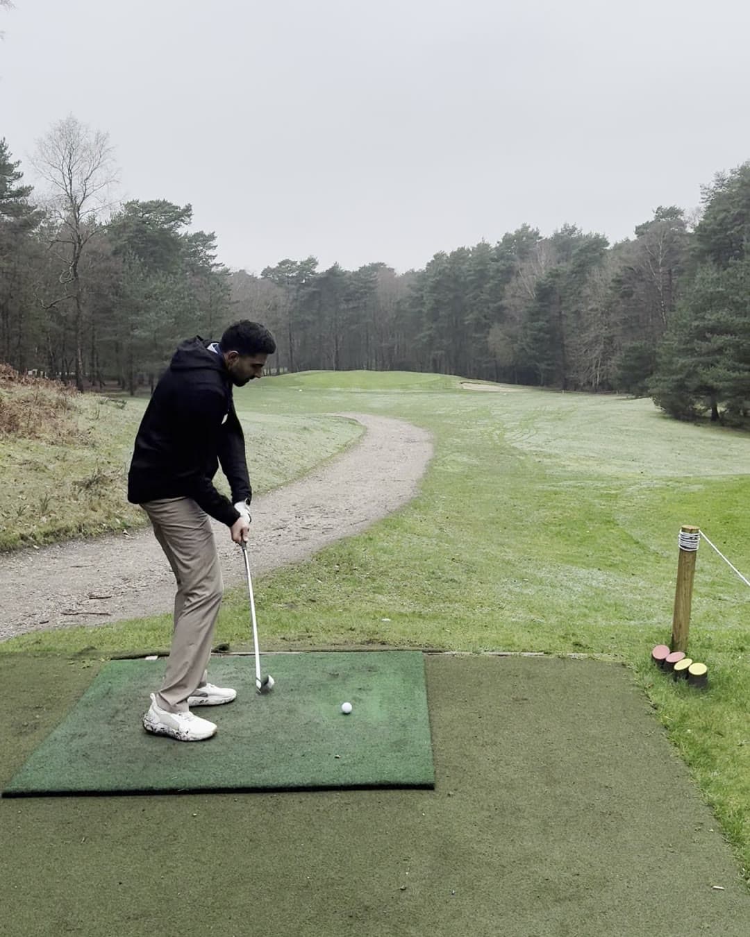 Param on the downswing with the club coming into the ball on a tee box mat