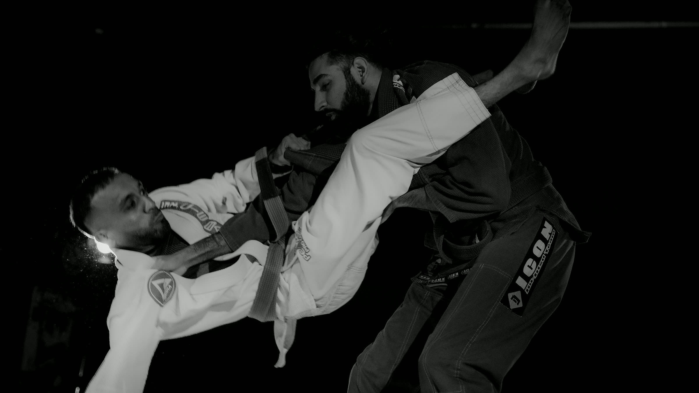 Brazilian jiu-jitsu — competition action shot, dark gi vs white gi