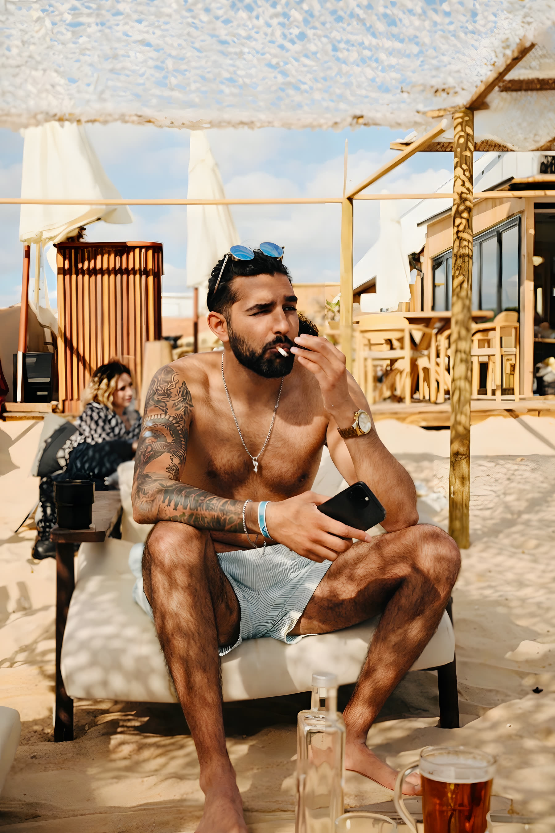Beach. Tattoo work visible — sleeve and chest piece.